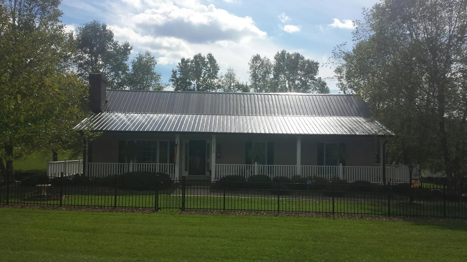 Gray metal roof on a brick ranch with a full width front porch — Gutter Guard Installation work by our crew in Riverton